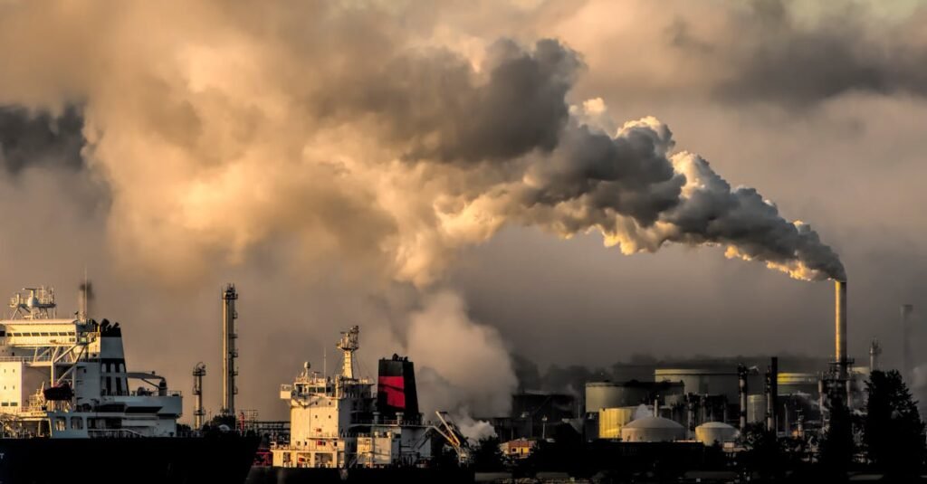 A dramatic capture of smokestacks releasing emissions over a waterfront, highlighting industrial pollution.